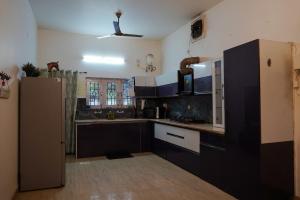 a kitchen with black and white cabinets and a refrigerator at Kudrat Villa with Private Pool in Dehradun