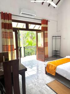 a bedroom with a bed and a desk and sliding glass doors at Aurelia Grand Hotel in Kitulgala