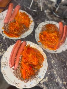 three plates of carrots and sausages on a table at Asylbek Guesthouse horseback riding tours in Kyzart