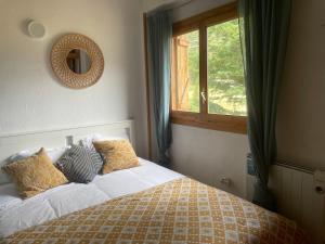 a bedroom with a bed with a mirror and a window at El rincón de la Rapeda in Villanúa