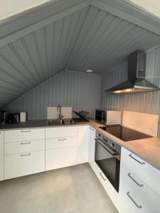 a kitchen with white cabinets and a gray ceiling at Studio by the river in Forshaga