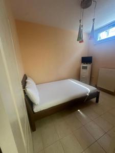 a small bedroom with a bed with white sheets and a window at MELIA Holidays & Living in Epanomi