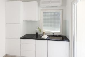 a white kitchen with a sink and a window at Aksa Residences in Vir +51 photos