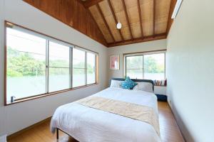 a bedroom with a bed and large windows at Miura Base in Miura