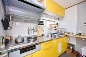 a kitchen with yellow cabinets and a stove top oven at Miura Base in Miura +26 photos