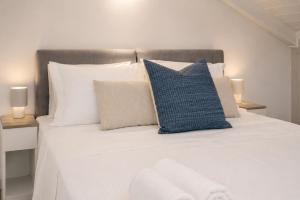 a bedroom with a white bed with blue and white pillows at Luminis Residence by All about Paxos in Gaios
