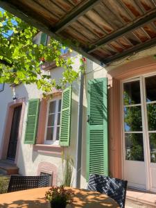 a patio with green shutters on a house with a table at Maison HELIOS - Eguisheim in Eguisheim