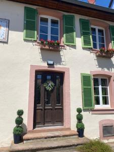 a house with green shutters and a wooden door at Maison HELIOS - Eguisheim in Eguisheim +16 photos