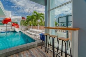 a pool with a slide and stools next to a building at พลอยพูลวิลล่า ชะอำ 2 Poolvilla Cha-am 2 in Cha Am