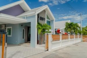 a house with a white fence and palm trees at พลอยพูลวิลล่า ชะอำ 2 Poolvilla Cha-am 2 in Cha Am