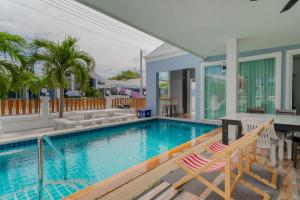 a swimming pool with two chairs next to a house at พลอยพูลวิลล่า ชะอำ 2 Poolvilla Cha-am 2 in Cha Am +54 photos