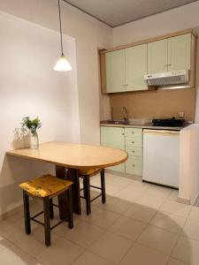 a kitchen with a wooden table and a table and stool at Skala Apartments in Agia Marina Nea Kydonias