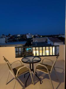 a table and two chairs on a balcony at night at Skala Apartments in Agia Marina Nea Kydonias