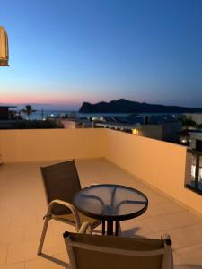 a table and a chair on a balcony at Skala Apartments in Agia Marina Nea Kydonias