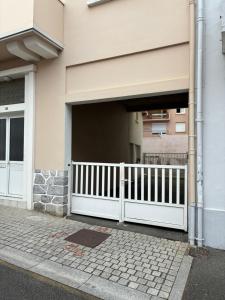 a house with a white fence in front of a garage at le duplex de l'Hôtel de ville in Lourdes