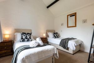 a bedroom with two beds and a mirror and two lamps at Braddon - Treworgie Barton Cottages in Bude