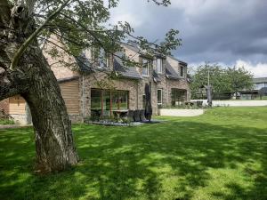 a house with a tree in front of a yard at Hof van Sassenbroek in Borgloon