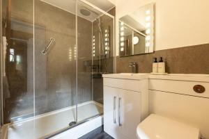 a bathroom with a shower and a toilet and a sink at Braddon - Treworgie Barton Cottages in Bude +24 photos