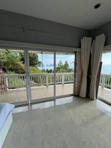 a bedroom with large windows and a balcony at The Sunset Suite Panoramic Sea Views in Sikao