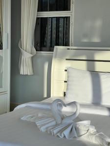 a white bed with a heart shaped towel on it at The Sunset Suite Panoramic Sea Views in Sikao
