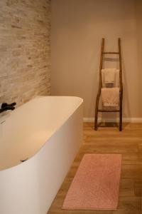 a bathtub in a room with a chair and a rug at Ons Hofke in Lubbeek +45 photos