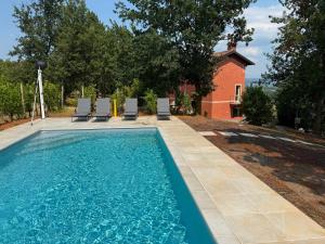a swimming pool with chairs and a house at Casia Vacanze con due appartamenti in Bene Vagienna