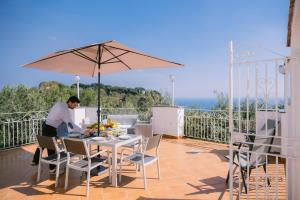a man sitting at a table on a balcony with an umbrella at Infinity Experience Casa Vacanza Incantevole con Terrazzo in Scala