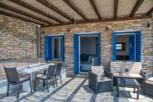 a patio with chairs and tables and a brick wall at Villa Anemelia Tinos in Agios Ioannis