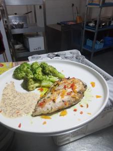 a plate of food with fish and broccoli on a table at Le Gite du Barrage in Zaouia Ben Smine