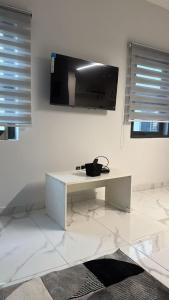 a white living room with a tv on the wall at Parkside City Apts in Accra