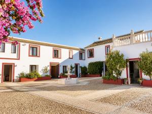 a large white building with red doors and trees at Cortijo Domínguez - Rural Experience in Lucena