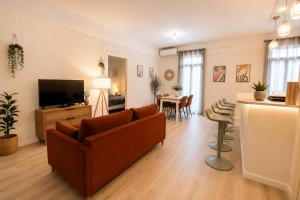 a living room with a couch and a television at Gare - Spacieux T2 avec Clim Balcon Wifi in Perpignan