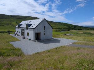 a small white building in a field with a hill at Lon Godrum in Kingsburgh
