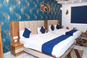a bedroom with two beds and a blue wall at Hotel Strawberry in Chandīgarh