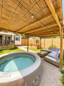 a patio with a hot tub under a wooden pergola at Le Soléa in Le Cailar