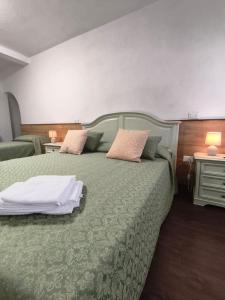 a bedroom with two beds with green sheets and pillows at Il Caminetto in Montecastrilli