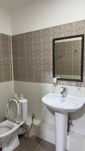 a bathroom with a toilet and a sink and a mirror at Белес in Astana