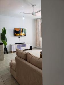 a living room with a couch and a tv on the wall at SPACIOUS VIP 1 BEDROOM with ROOFTOP SWIMMING POOL AVAILABLE in Mtwapa