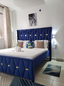 a blue bed with a large blue headboard in a room at SPACIOUS VIP 1 BEDROOM with ROOFTOP SWIMMING POOL AVAILABLE in Mtwapa +32 photos