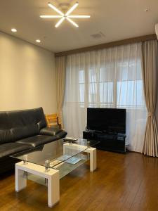 a living room with a black couch and a television at Mon Petit Chat in Kanazawa