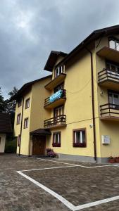 a yellow building with a parking lot in front of it at Łopiennik in Cisna