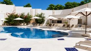 a swimming pool with chairs and umbrellas at The Amman Landmark Hotel in Amman