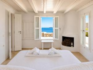 a white bedroom with a large bed and a window at Folegandros Villas Aspropounta Double Room Beachfront in Chora Folegandros +40 photos