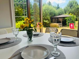 a table with plates and glasses and a vase with yellow flowers at Dom w Niechorzu dla 8 osób z dużym ogrodem - 5D Apartments in Niechorze