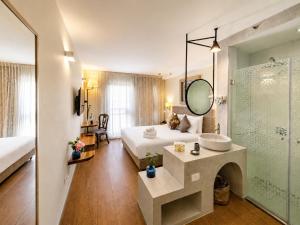 a bedroom with a bed and a sink and a mirror at Margosa Boutique Hotel Tel-Aviv Jaffa in Tel Aviv