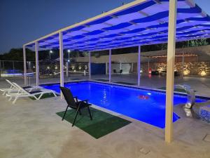 a swimming pool under a blue canopy at night at Ayla Shalet Villa in Al Kufayr