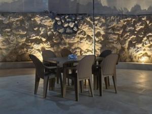 a dining room table with chairs and a stone wall at Ayla Shalet Villa in Al Kufayr