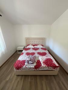 a bedroom with a bed with a red and white quilt at Apartman Sambi 3 in Čanj
