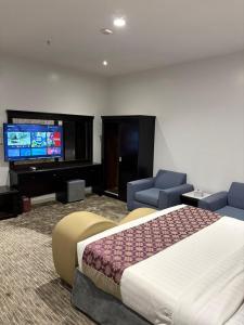 a hotel room with a large bed and a flat screen tv at Pherbion Hotel Apartment Abha in Abha