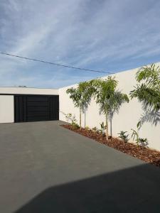 a white building with a garage and palm trees at Lotus in Gurupi